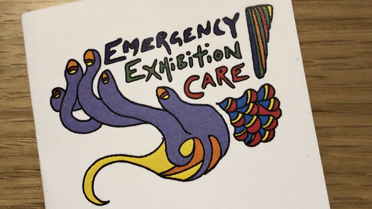 A photo of a zine that say 'Emergency Exhibition Care'