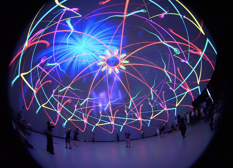 Fisheye view of the Satosphère dome lit up with a do-em, players standing on the floor below