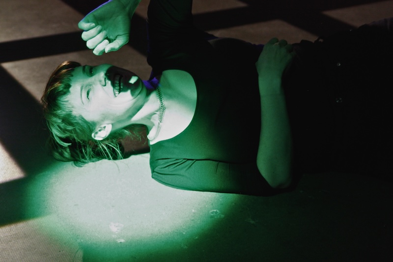 A playtester lying on the ground, laughing, lit by a green spotlight
