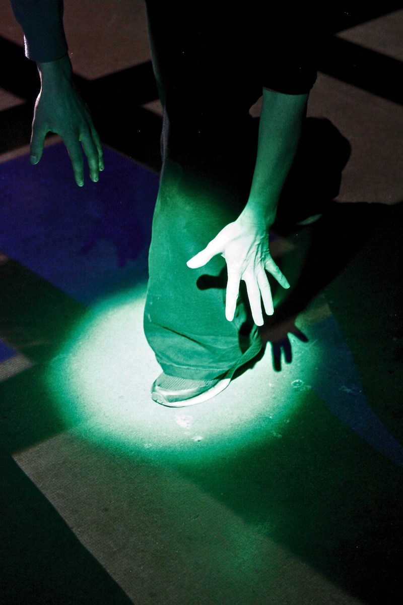 A playtester's hand and foot reaching into a green spotlight on the ground