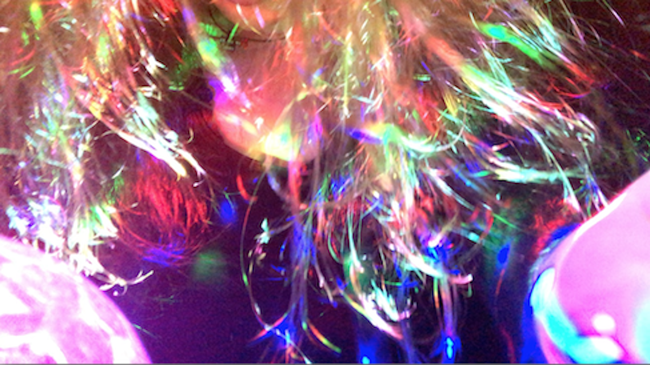 Closeup of colourful lights on a blurry person.